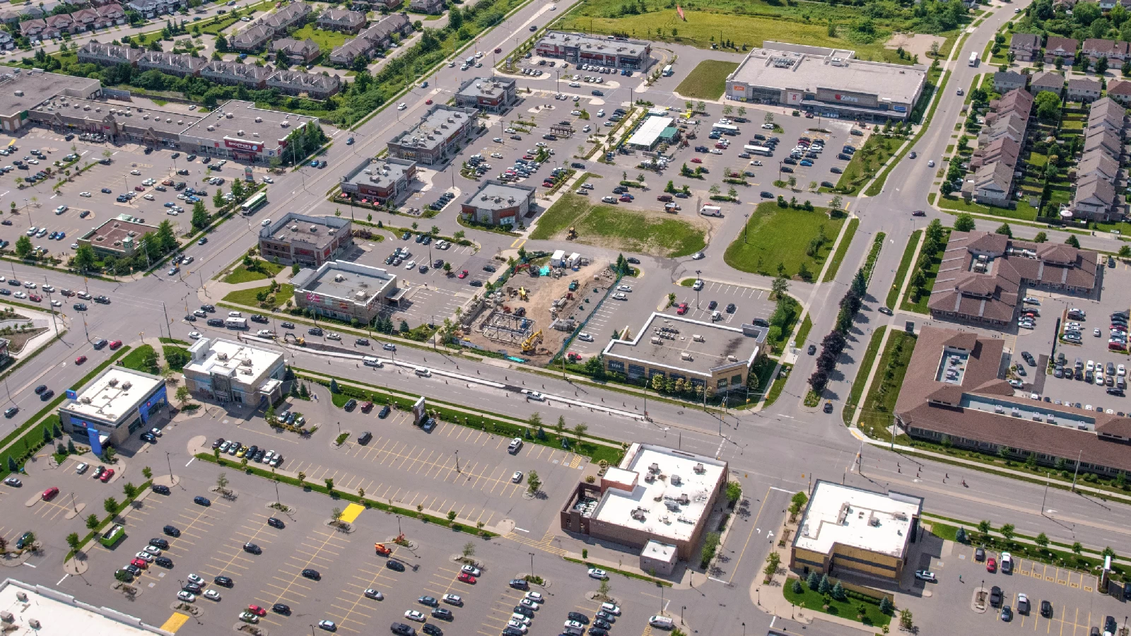 Clair Rd E & Gordon St (NEC), Guelph – aerial view of the plaza and parking lots among commercial buildings