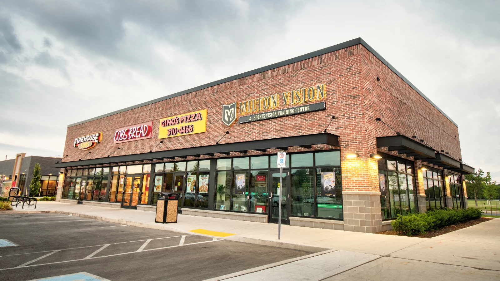 Willmott Marketplace, Milton – brick retail row with parking at dusk