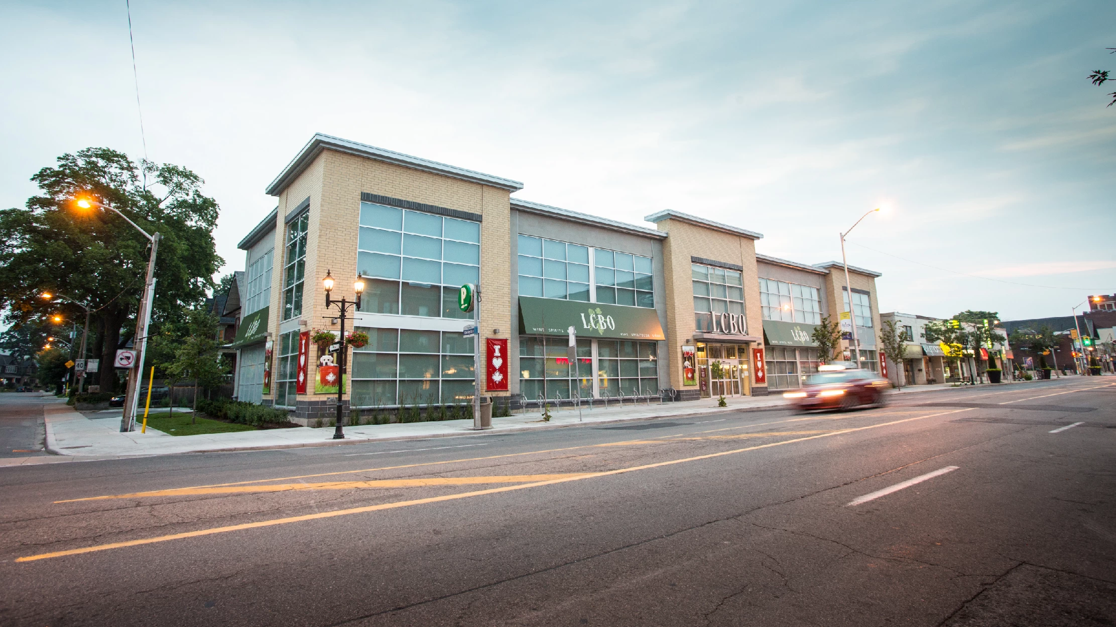 Danforth Ave & Ellerbeck St, Toronto – two-storey retail building with LCBO from across the street at dusk