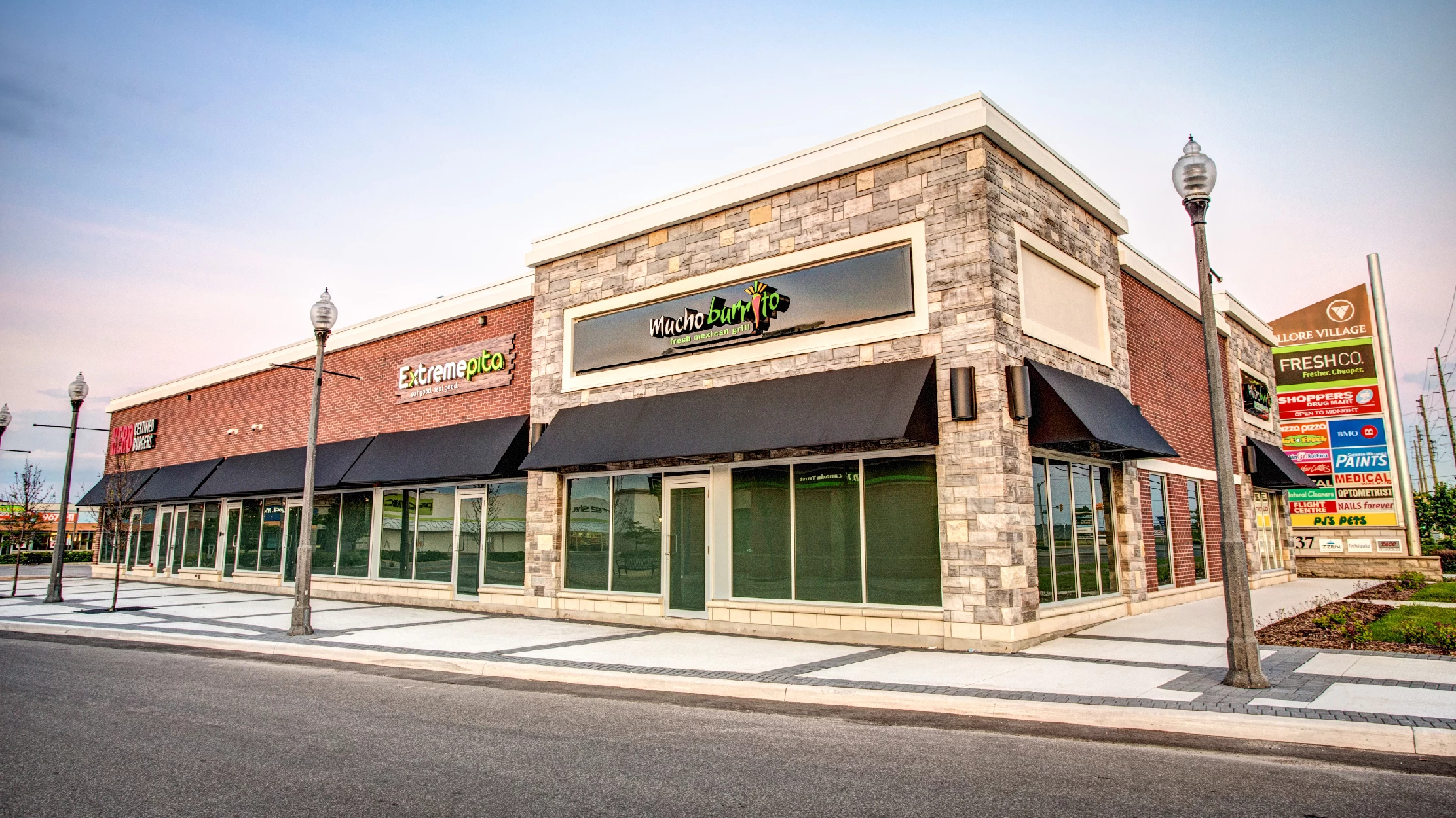 Vellore Village Phase I, Vaughan – stone-clad retail row with a FreshCo pylon sign at dusk