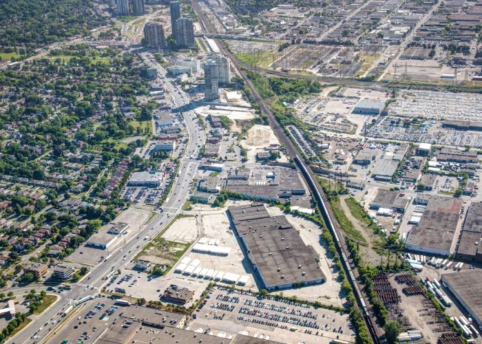 Honeydale Mall Redevelopment, Toronto – aerial view of the mall and parking lots beside a rail corridor