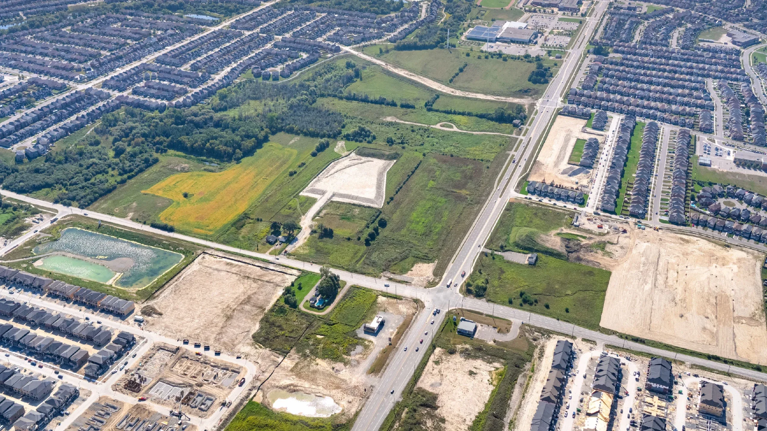 Conlin and Harmony Rd N, Oshawa – aerial view of the undeveloped site beside subdivisions and a pond