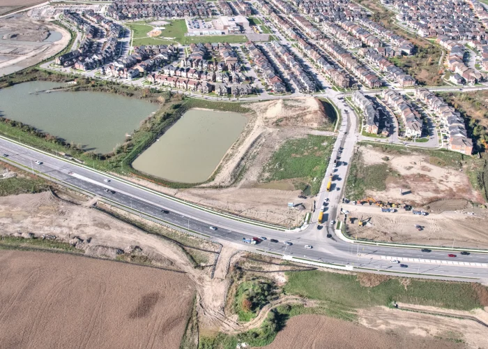 New Kleinburg Marketplace, Kleinburg – aerial view of the undeveloped site with a pond beside a highway