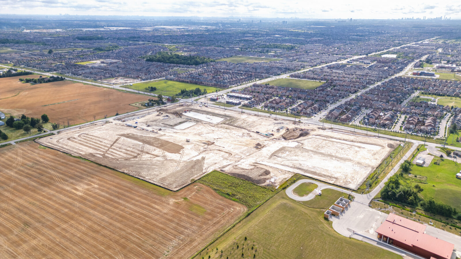 Mayfield Road and Creditview Road, Caledon – aerial view of the graded site with farmland and a subdivision beyond