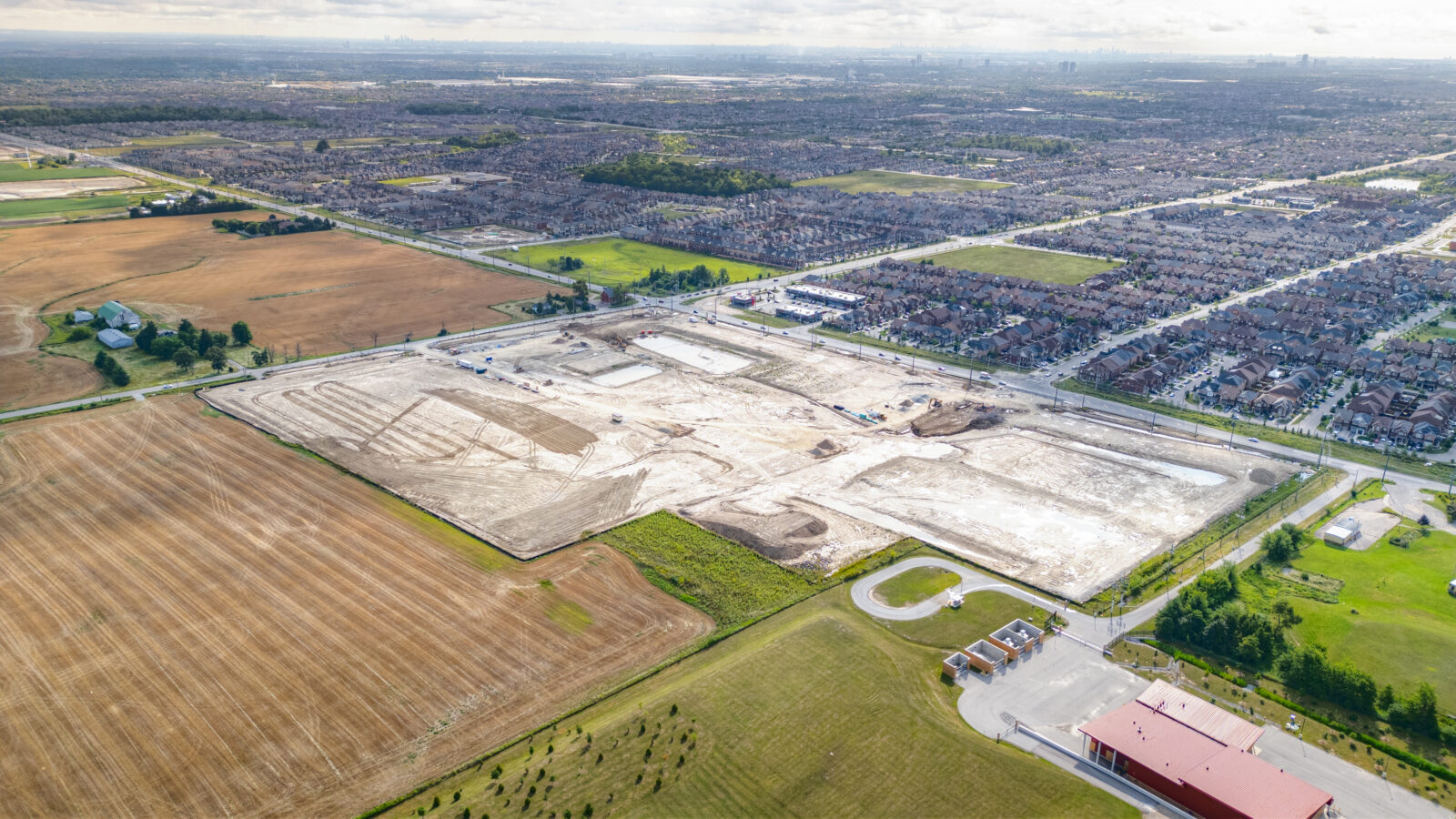 Mayfield Road and Creditview Road, Caledon – aerial view of the graded site with farmland and a subdivision beyond