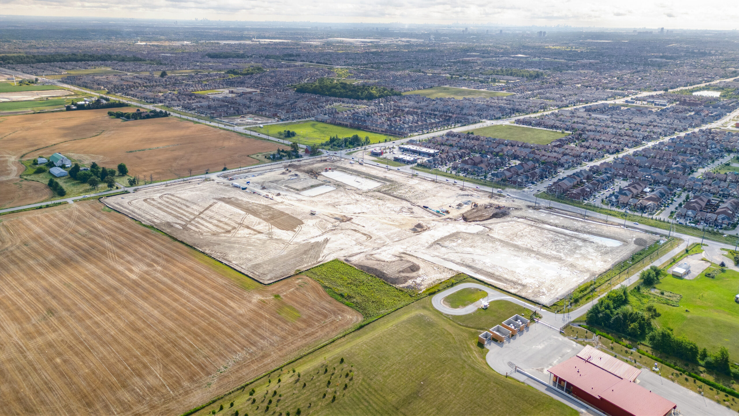 Mayfield Road and Creditview Road, Caledon – aerial view of the graded site with farmland and a subdivision beyond