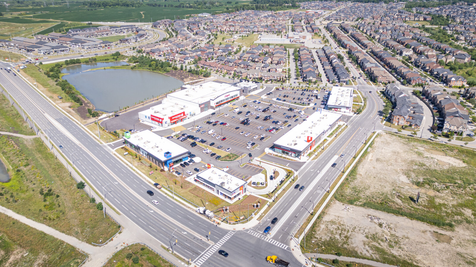 New Kleinburg Marketplace, Kleinburg – aerial view of the plaza, parking lot and pond beside a highway