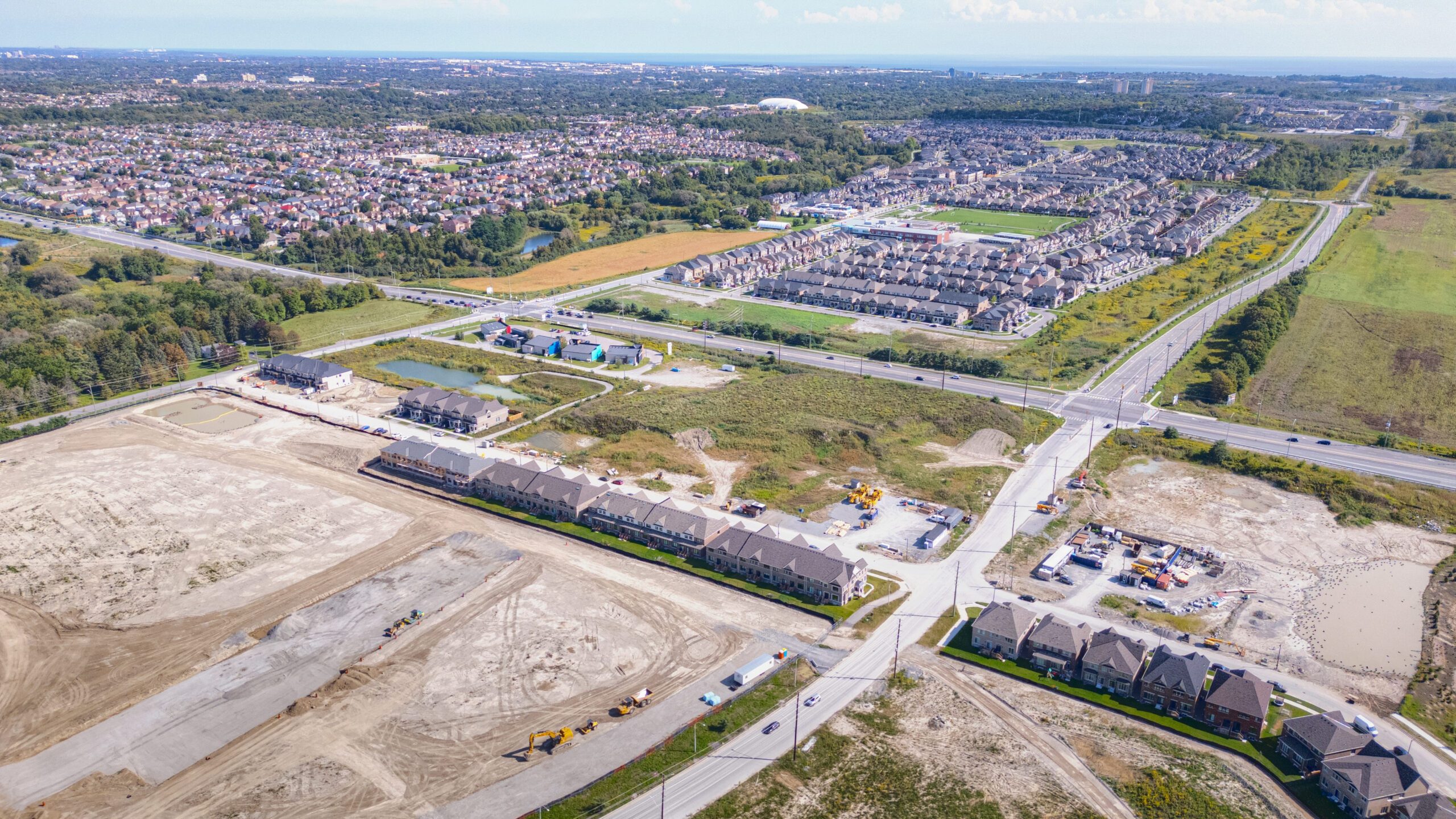Taunton Rd W & Des Newman Blvd, Whitby – aerial view of the graded site beside a new subdivision