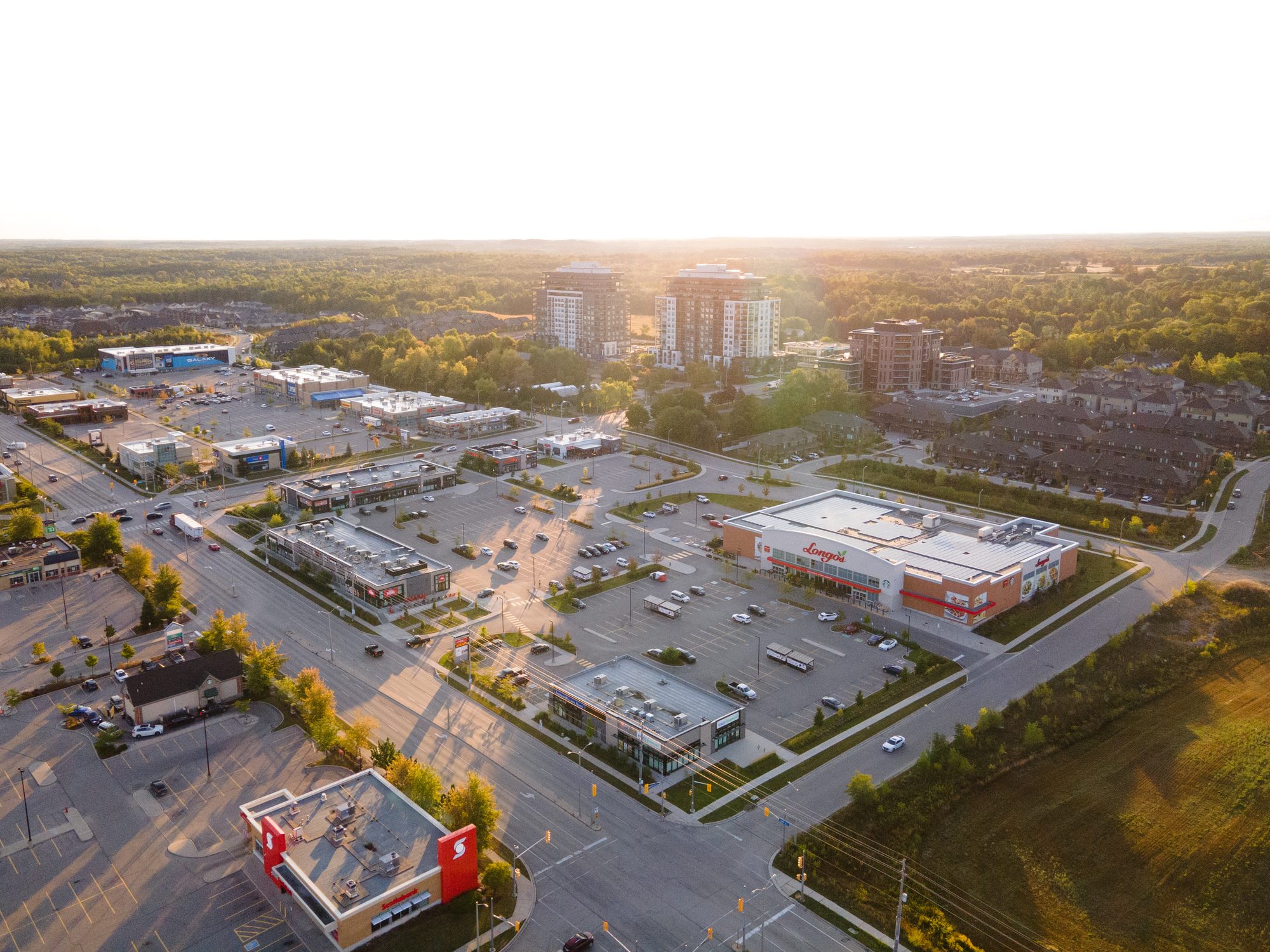 Clair Rd E & Gordon St (NEC), Guelph – aerial view of the plaza at sunset with condo towers beyond