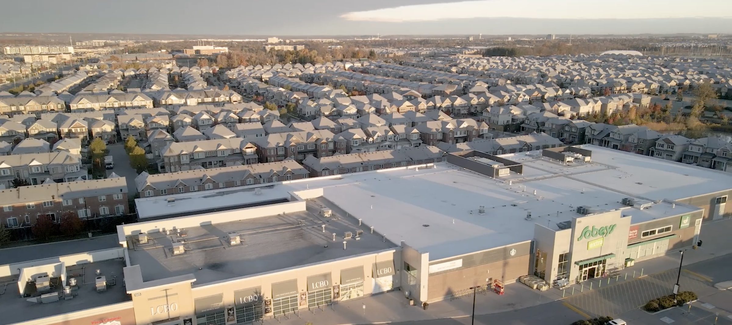 Fieldgate Commercial – aerial view of the plaza rooftop and parking lot beside a subdivision