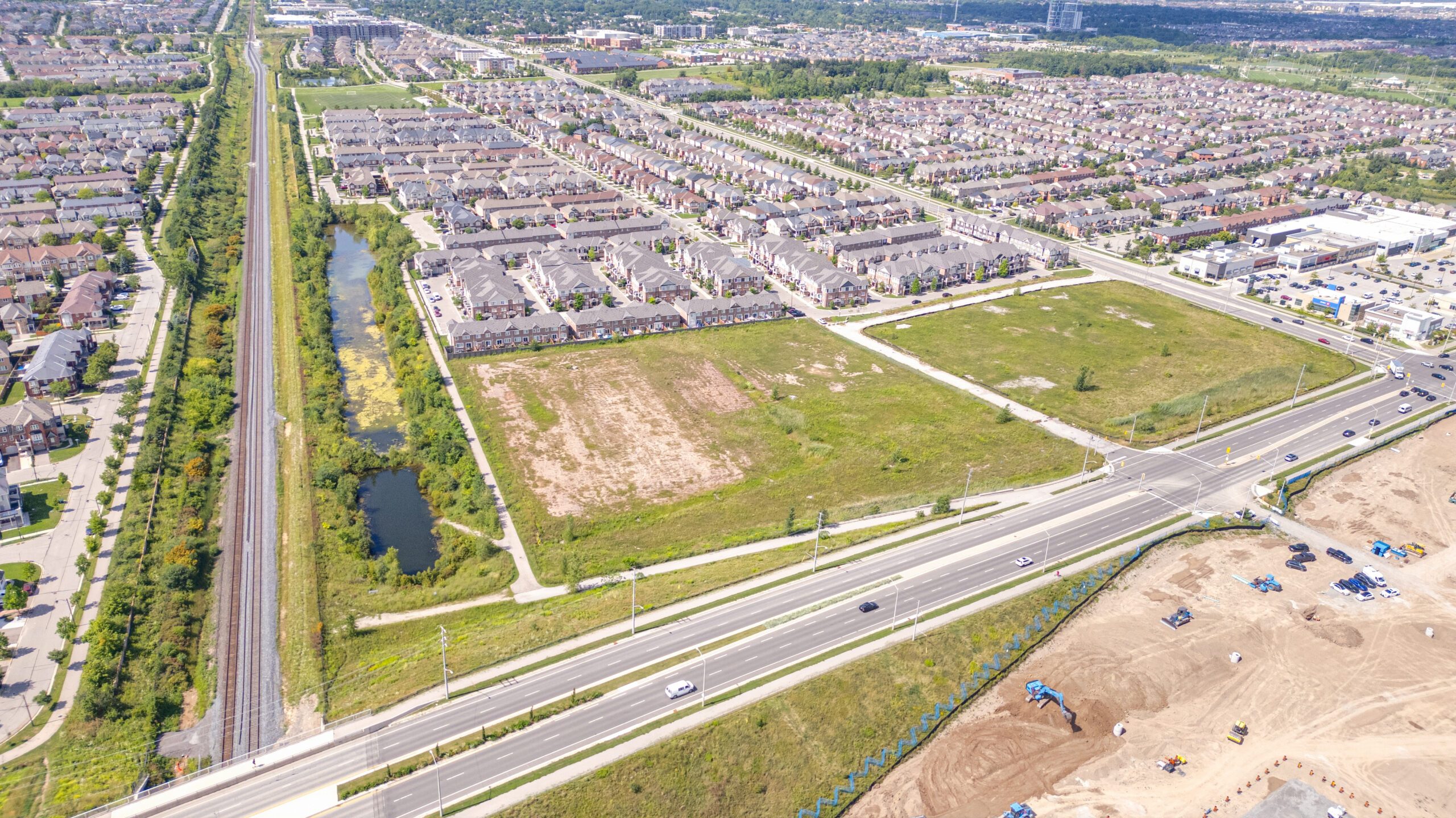 Asleton Blvd & Louis St Laurent Ave, Milton – aerial view of the graded site beside a subdivision and road