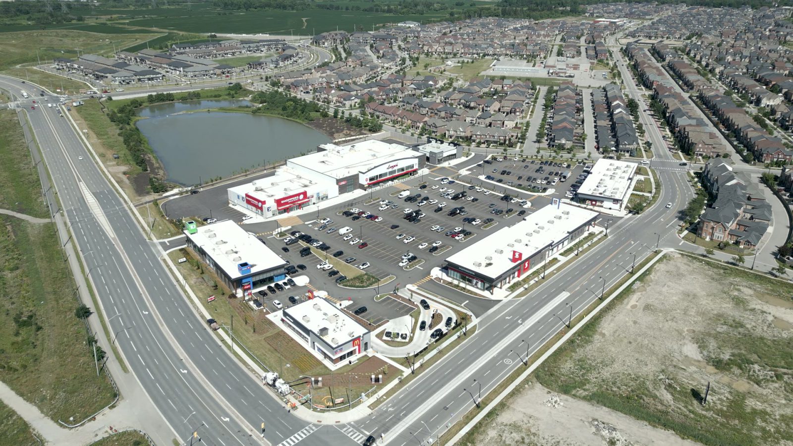 New Kleinburg Marketplace, Kleinburg – aerial view of the plaza and parking lot beside a highway and pond